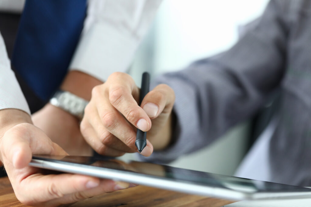 Zwei Personen, die mit einem Tablet arbeiten, eine Person hält einen Stylus.